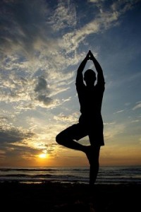 Picture of man doing tree pose with sun-set behind him